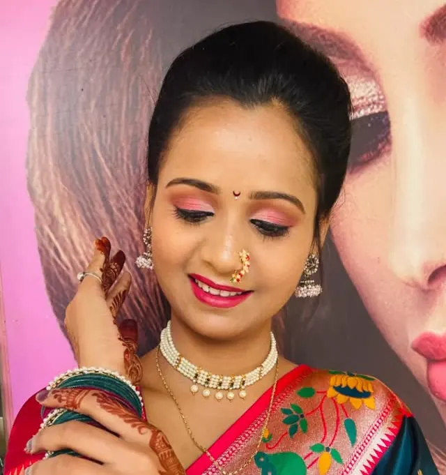 Close-up of a bride in a paithani saree with a nath and a pearl choker, mehendi on her hands. Makeup by Hema.