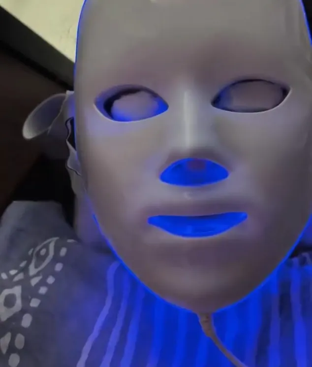 An LED light mask glowing blue on a client’s face during a facial at the salon.