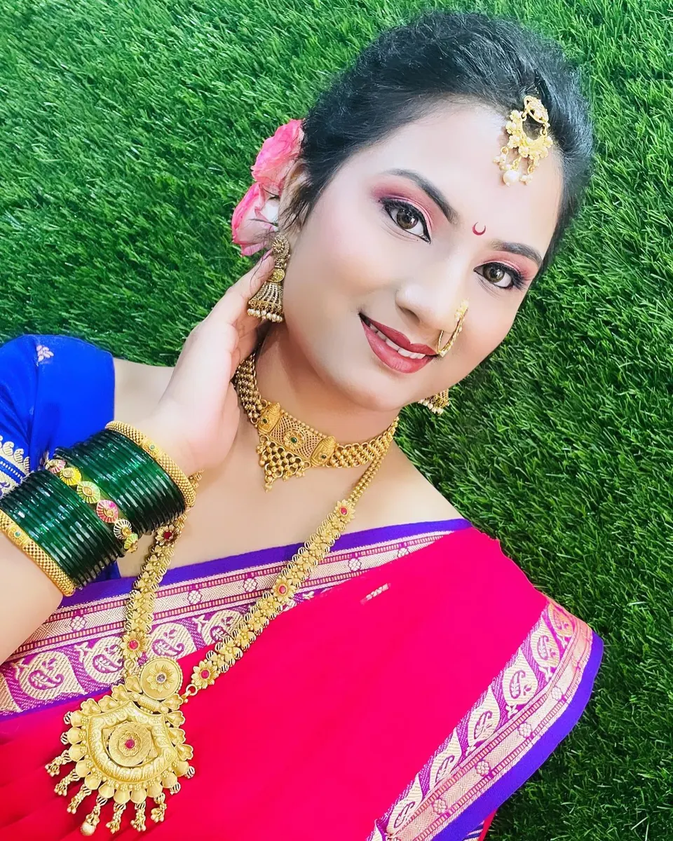 Maharashtrian bride in a pink silk saree with green bangles, a nath and a maang tikka, smiling at the camera. Makeup by Hema.