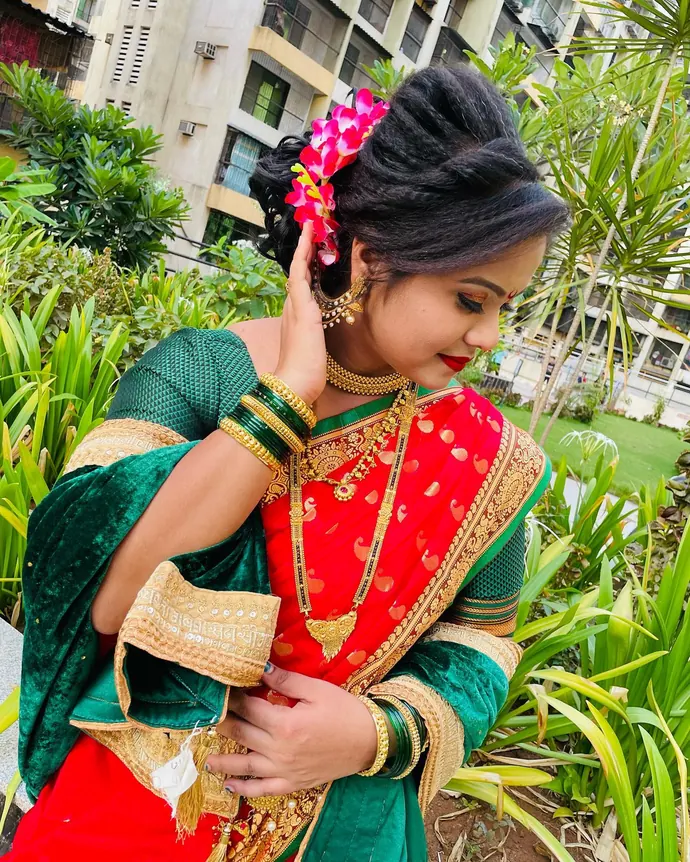 Maharashtrian bride in a nauvari saree with a nath and pink flowers in her hair, looking down.